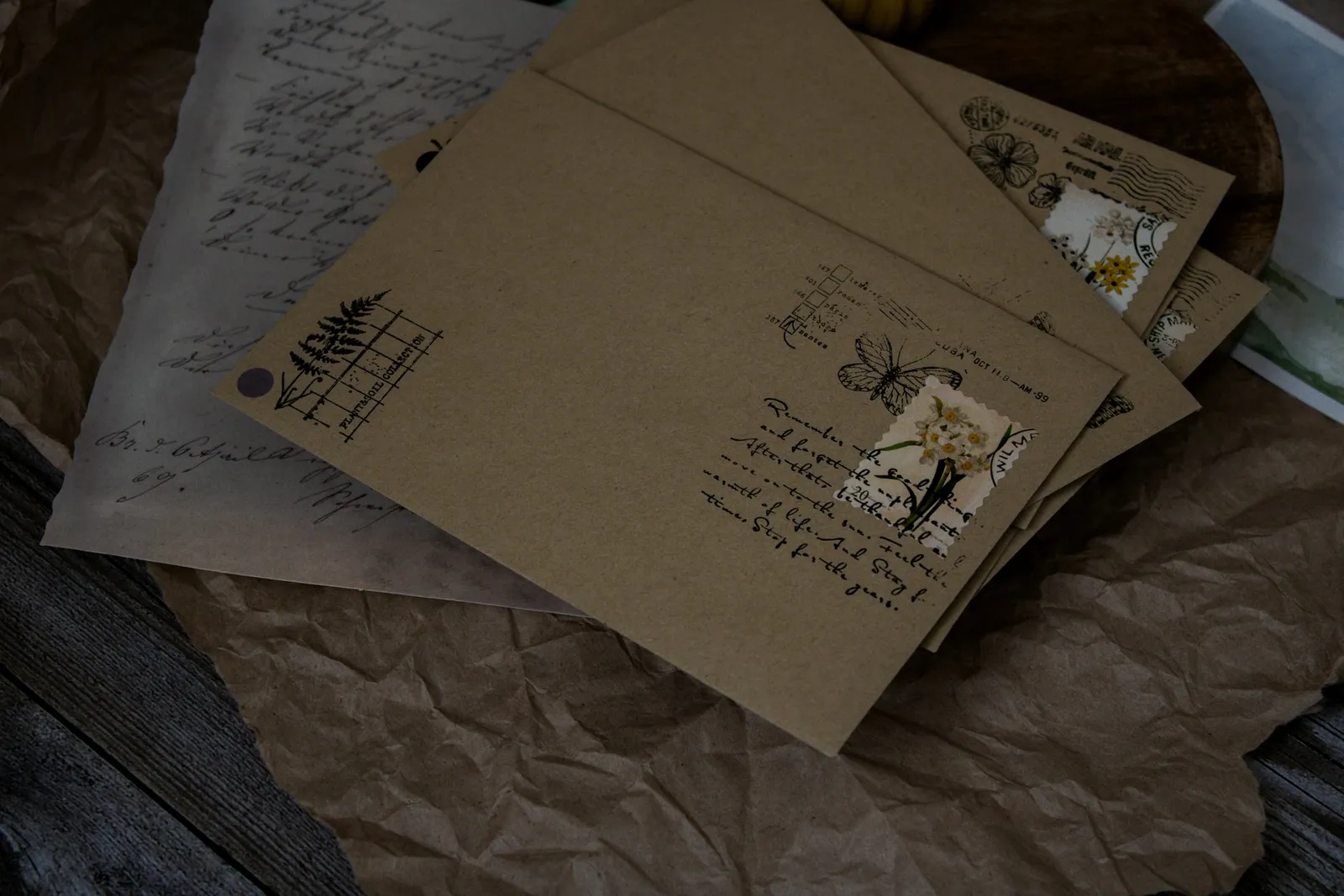 Stack of vintage envelopes with botanical stickers and decorative stamps arranged on a wooden table surface