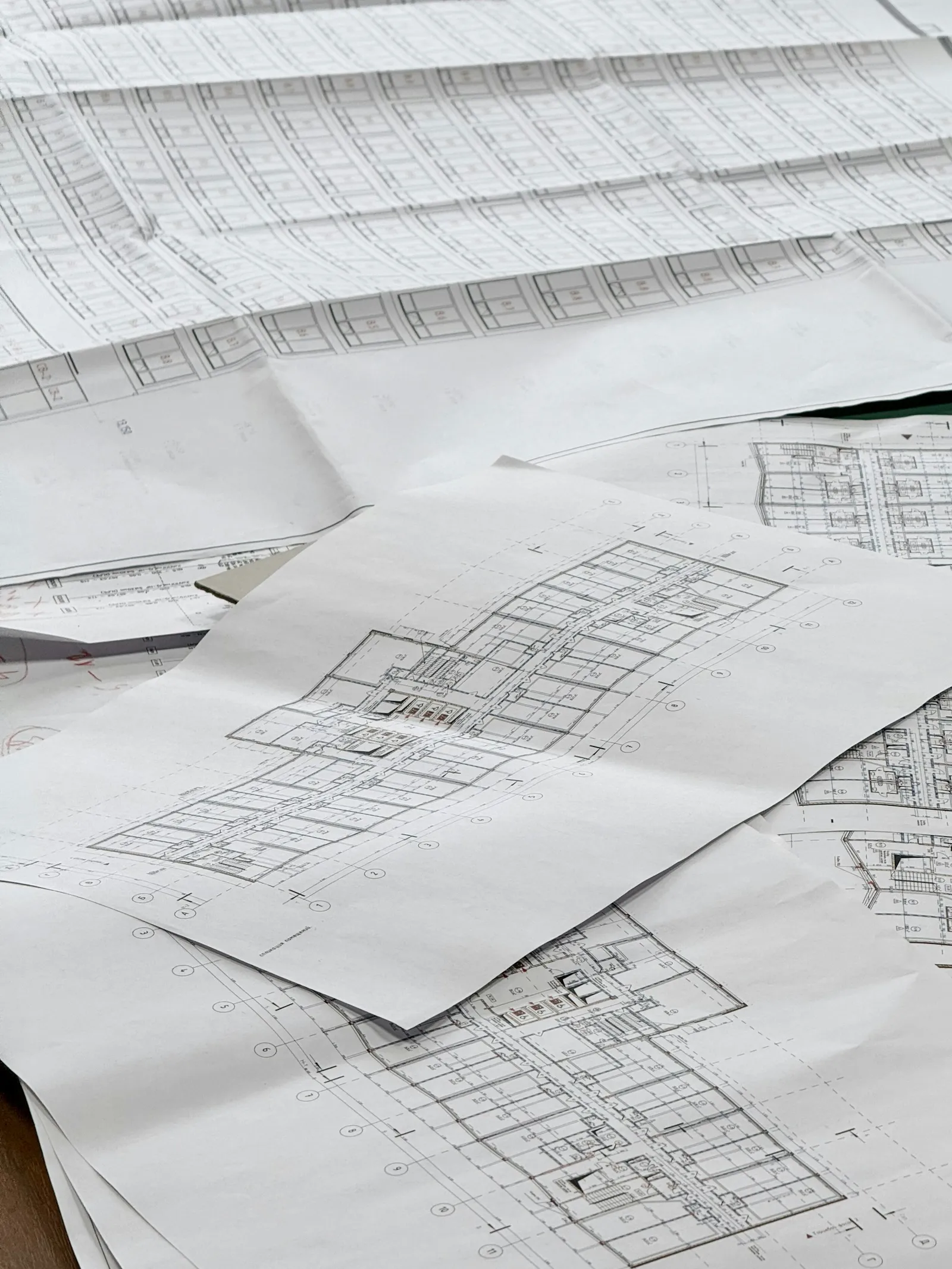 Overhead view of architectural blueprints unrolled on a flat surface showing floor plan line drawings