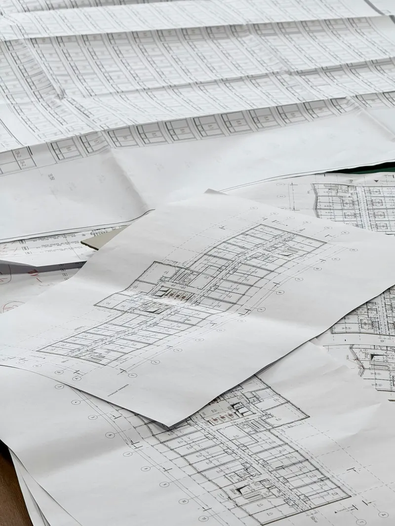 Overhead view of architectural blueprints unrolled on a flat surface showing floor plan line drawings
