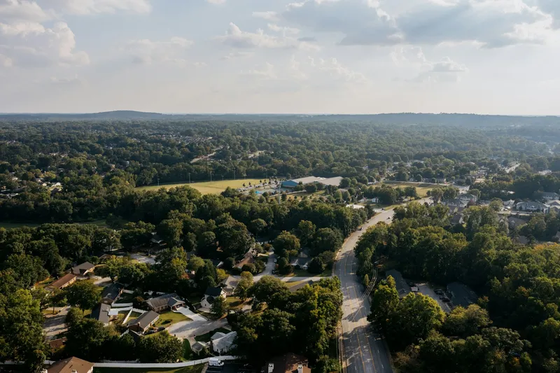 Aerial view of a suburban neighborhood with houses set among lush green trees and winding residential streets