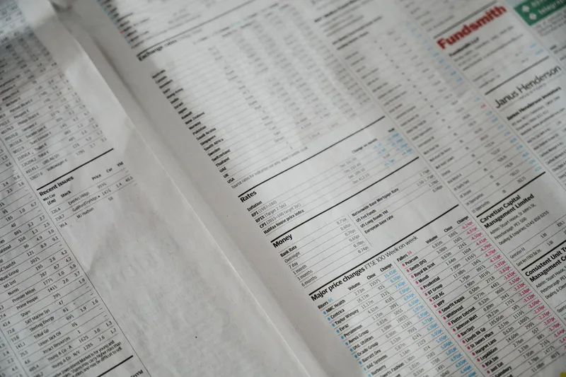 Close-up of a newspaper finance section with rows and columns of small printed numerical data in grey tones