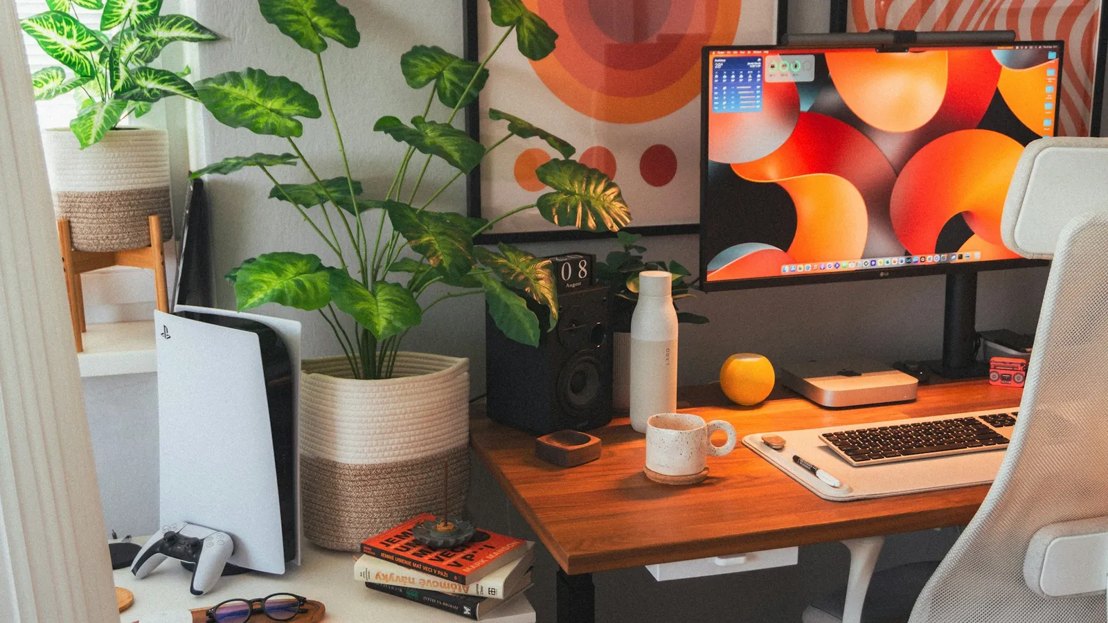 Silver laptop sitting on a light wooden desk next to a small potted green plant in soft natural light