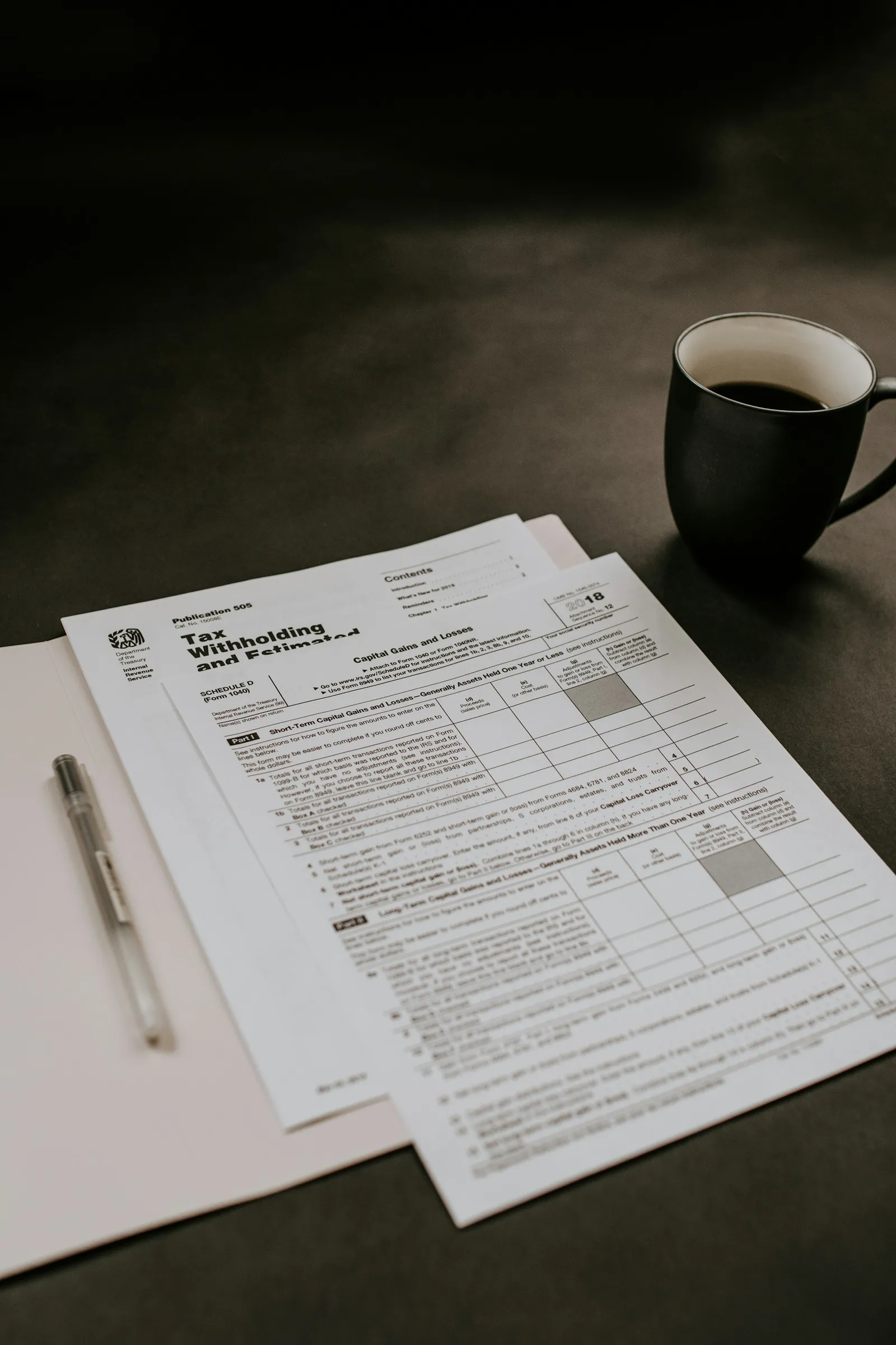 Stack of blank white papers next to a calculator, pen, and black ceramic coffee mug on a light marble surface