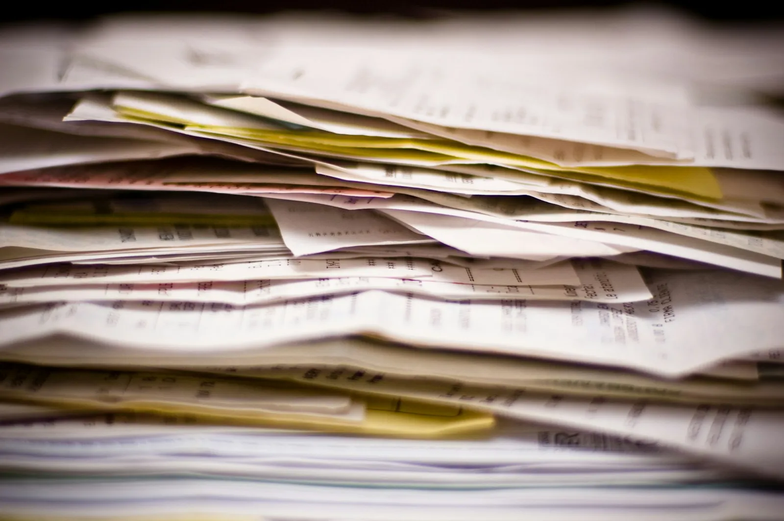Close-up of a thick stack of printed papers, invoices, and receipts piled together on a flat surface