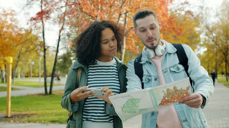 Couple standing close together outdoors holding an open paper map between them, laughing while pointing at a route on a city street